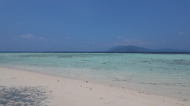 Clear turquoise water and white sand beach at Cemara Kecil island, shallow coral reef seascape, tropical holiday destination, peaceful nature background for travel and lifestyle projects. Time lapse.