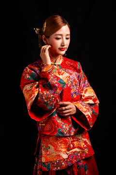 Bridal look featuring traditional Chinese red wedding attire against a black background.