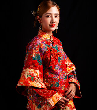 Bridal look featuring traditional Chinese red wedding attire against a black background.
