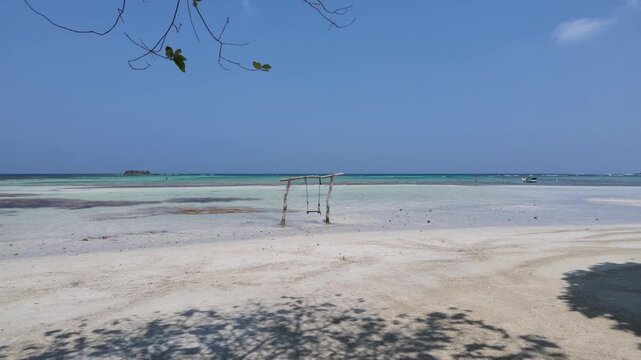 Framed view through palm trees of a serene sandy beach in Karimunjawa with clear turquoise waters, gentle tide, tropical island atmosphere, calm coastal scenery, paradise travel destination