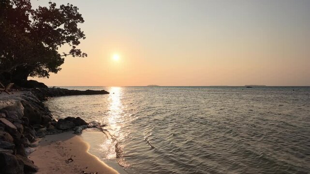 Golden sunset over calm tropical ocean waters at Karimunjawa island, gentle rippling sea waves washing sandy coastline, serene dusk atmosphere, peaceful horizon, travel destination landscape