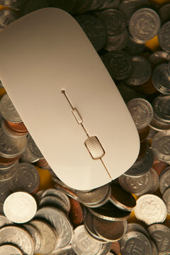 White computer mouse with gold coins on yellow background