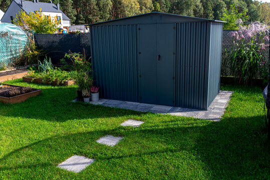 Metal garden shed standing on paving slabs in backyard
