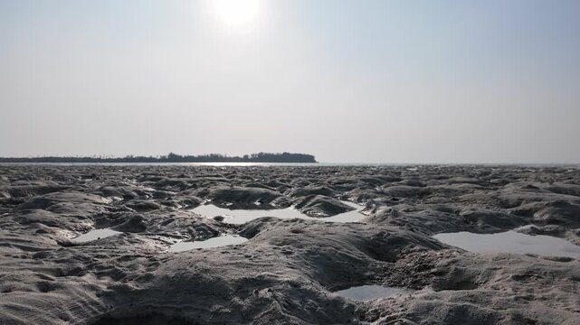 Slow motion. Low tide at Karimunjawa islands in Indonesia with vast mudflats, shallow tidal pools, reflections of sun, coastal horizon line, atmospheric tropical shoreline, ideal for travel and nature