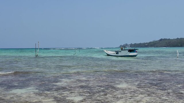Small fishing boat anchored in shallow turquoise tropical waters near Karimunjawa coastline, summer vacation travel destination, maritime transport, remote island paradise, relaxing marine scenery
