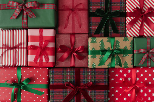 Red and green Christmas presents arranged as a decorative background. Festive wrapped Christmas gift boxes  with ribbons and holiday patterns. 