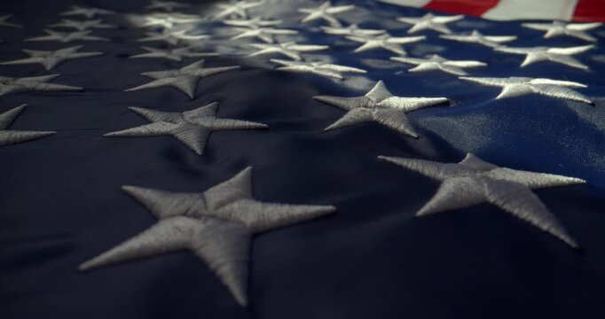 Close-up cinematic shot of the United States flag lying on a horizontal surface under directional local light. Slow push-in camera movement captured with a probe lens and slider.