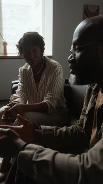 Vertical shot of African American man speaking and gesturing during counseling session with African American woman. Ideal for mental health, therapy, and psychological wellness advertising