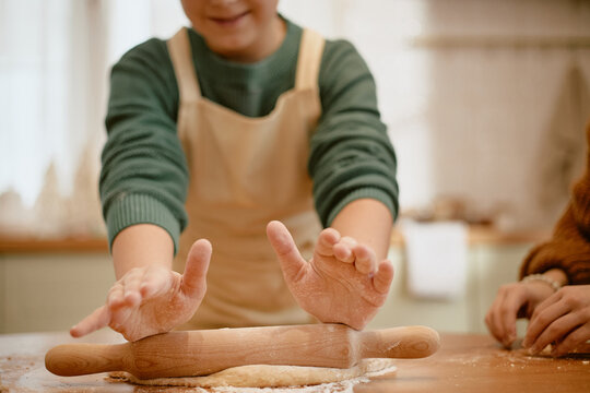 Caucasian child rolling dough with rolling pin alongside grandmother during baking activity. Useful for culinary education, family lifestyle promotions, and cooking classes