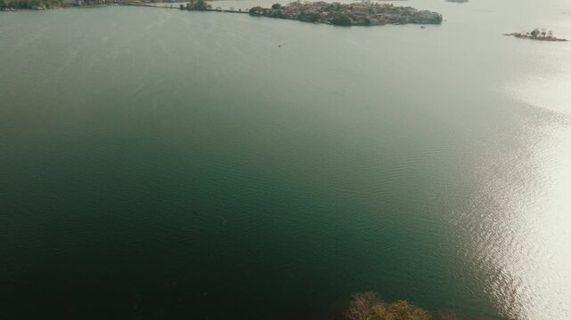 Aerial view of the lush vegetation and shoreline of Flores Island surrounded by the calm waters of Lake Peten Itza in Flores, Peten Department, Guatemala.