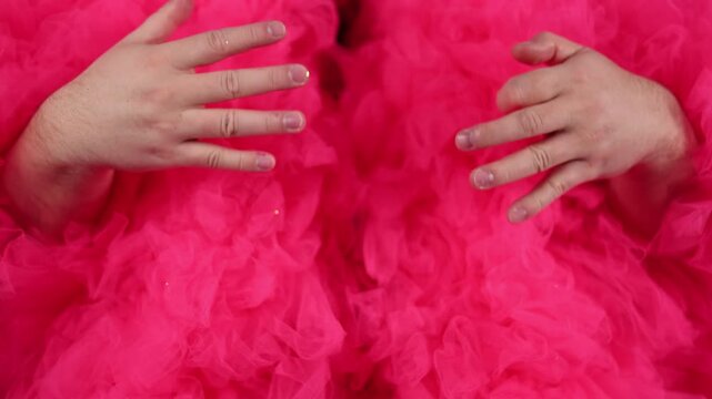 Defocused 4K video close up. Two male hands touching vibrant pink fluffy tulle fabric texture with soft folds and ruffles, magenta fur coat, dress, costume details. Dance, lgbt, diverse beauty, disco