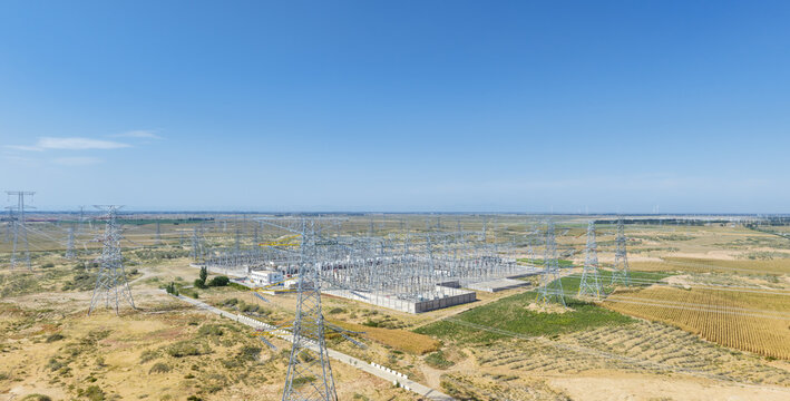 Aerial Panorama of a Large High-Voltage Substation with Transmission Towers on Arid Sandy Land