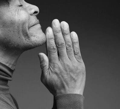 praying to god with hands showing his religious faith with God Caribbean man praying with background with people stock photo stock image