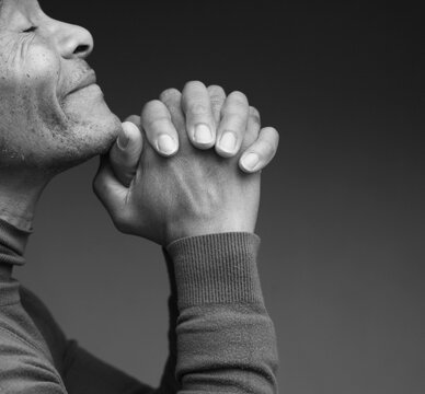 praying to god with hands showing his religious faith with God Caribbean man praying with background with people stock photo stock image