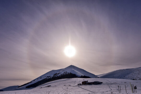 View of a sun halo over the snow-covered slopes of the Apennine Mountains near Castelluccio, Umbria, Italy.
