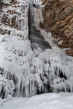 View of the frozen Cascate del Pisciatore waterfall with massive icicles and snow-covered rocks in the winter landscape of Castelsantangelo sul Nera, Marche, Italy.