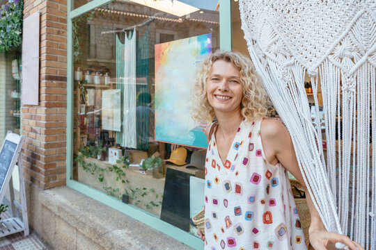 Stylish mature woman discovering handmade macrame at creative boutique in small Spanish town