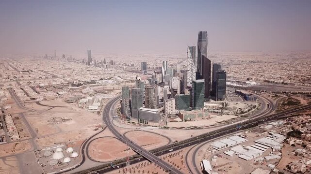 Aerial drone view showcasing modern skyscrapers and highway interchanges in a sprawling city landscape.