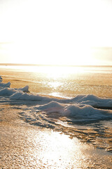 Ice floes on frozen seashore with sparkling sun reflection on water at winter sunset, Yyteri beach, Finland © Alina Mir