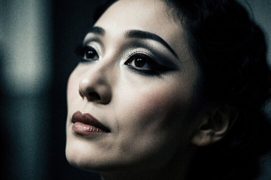 Close up portrait of trans person with dramatic makeup. Crossdresser performer wears heavy eyeliner, dark lipstick for theater show. Glamour style face of beautiful person with artistic look in New