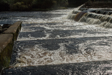 The River Ure cascades over a weir at Boroughbridge in Yorkshire, creating turbulent white water and foam. © SteveGillPhotography