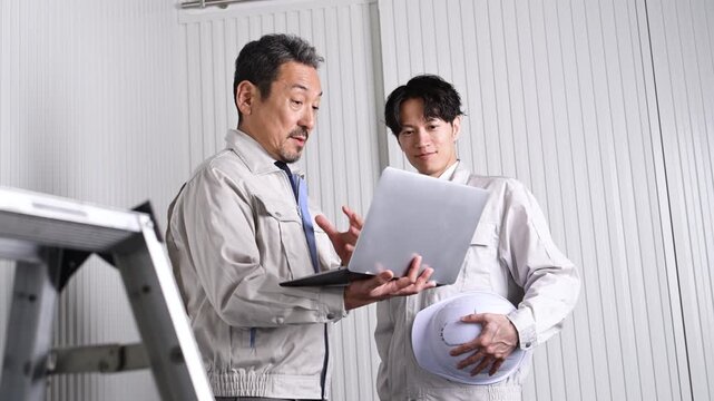 パソコンを見ながら打ち合わせを行う30代と50代の日本人技術者