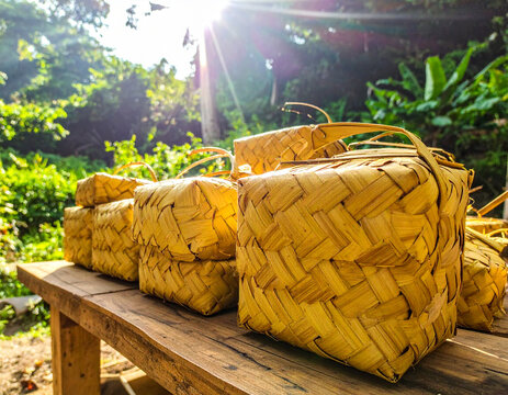 Handwoven Palm Leaf Containers Stacked on Wooden Table in Sunlight