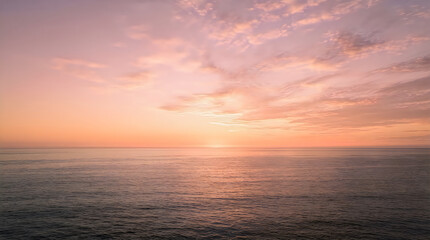 Fototapeta premium A serene ocean view during a beautiful pastel sunset with soft clouds above the calm water horizon