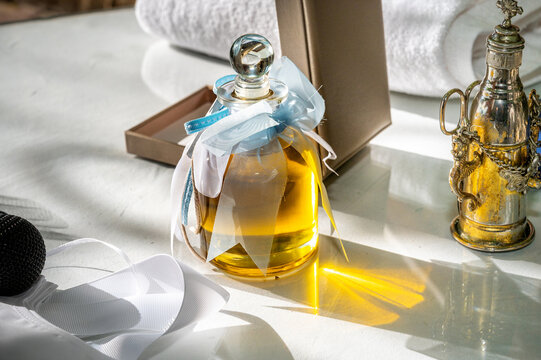 Decorated glass bottle filled with golden baptismal oil, adorned with white and blue ribbons and placed beside traditional Orthodox baptismal objects during a Greek christening ceremony.