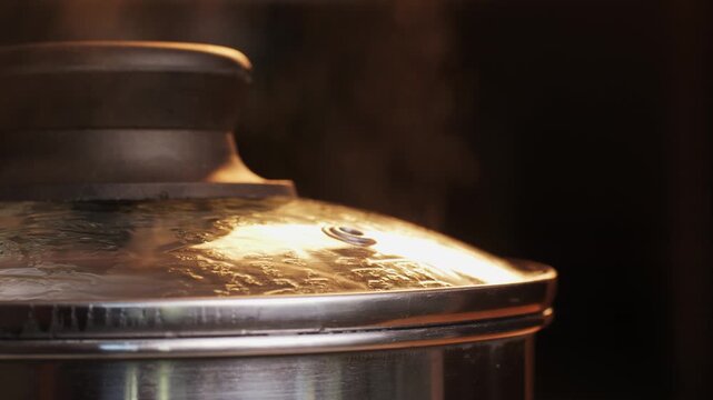 Stainless steel pot on a gas stove with boiling water and steam, cooking soup