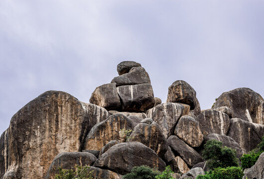 View of the rugged granite rock formations of Shere Hills under a cloudy sky in Shere Hills, Plateau, Nigeria.