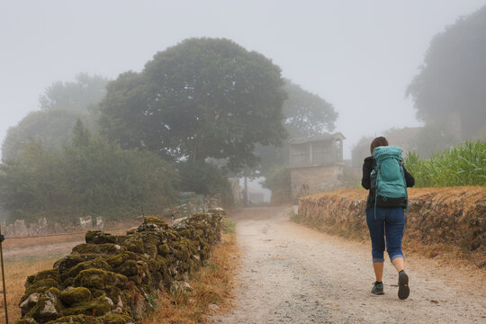 Pilgrim walking on a foggy rural path, Camino Primitivo, Spain