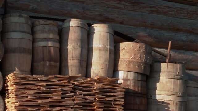 Close-up shot of hand-crafted wooden barrels, carved tubs, and wooden roof shingles stacked
 outside an authentic log house in a Carpathian village. Showcasing traditional woodworking craftsmanship

