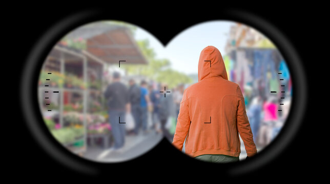 Binoculars Point of View (looking through binoculars),Rear view of a hooded criminal. Surveillance of criminals. 