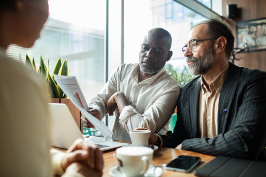 Businessmen presenting a report to a client in a cafe
