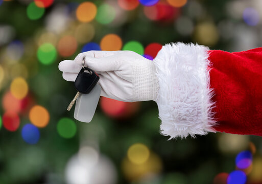 Shot of an Santa Claus hand giving a car key at home with christmas tree