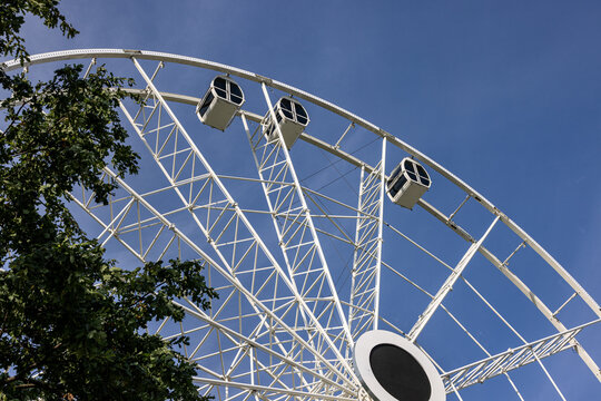 View of the white Ferris wheel structure with passenger cabins against a clear blue sky in Kaunas, Kaunas County, Lithuania.