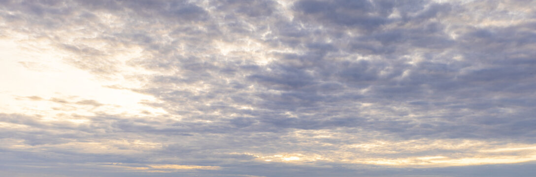 Panoramic Golden Sunset Sky Background with Cloud Texture,A wide-angle panoramic view of a dramatic sunset sky filled with dappled clouds glowing in golden sunlight. Ideal for sky replacement, nature 