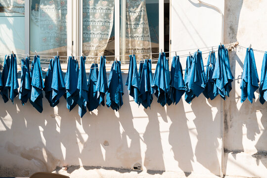 View of blue cloths hanging on a clothesline against a white wall in Procida, Campania, Italy.