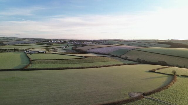 Aerial view of rolling green agricultural fields and hedgerows in the rural countryside of Looe, England, United Kingdom.