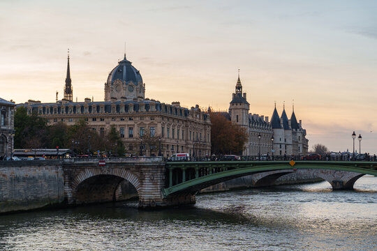 Historic Paris bridges cross the Seine beneath the ornate architecture of &Icirc;le de la Cit&eacute; - view on Tour de l'Horloge du Palais de la Cit&eacute;