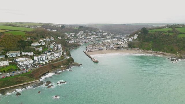 Aerial view of Banjo Pier and Looe Beach with the town nestled along the river mouth and coastline on an overcast day in Looe, England, United Kingdom.