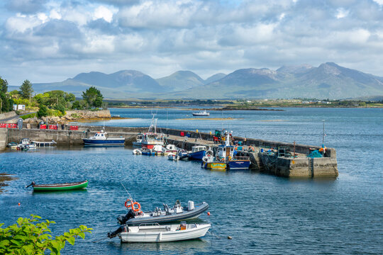 Irish harbor of Roundstone with colorful fishing boats, Connemara mountains background, County Galway, Ireland