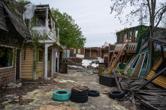 View of dilapidated wooden structures and abandoned buildings with overgrown vines and scattered tires in a desolate area in Bulgaria.