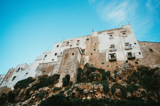 View of the historic white buildings perched on the rugged limestone cliffs overlooking the sea in Polignano a Mare, Apulia, Italy.