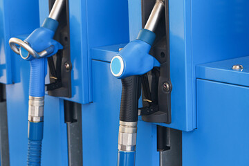 Blue fuel pump nozzles at filling station. Petrol and diesel dispenser equipment. Automotive refueling background. Metal hoses and handles for fuel supply. Transportation energy infrastructure. © Paweł Michałowski