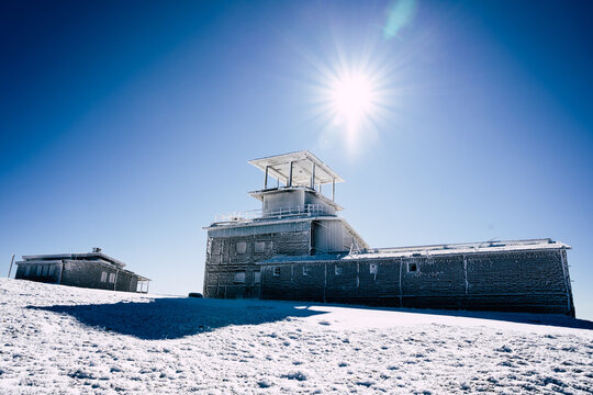 View of the frost-covered Golyam Kademliya Shelter on a snowy mountain peak under a clear blue sky in Stara Zagora, Bulgaria.