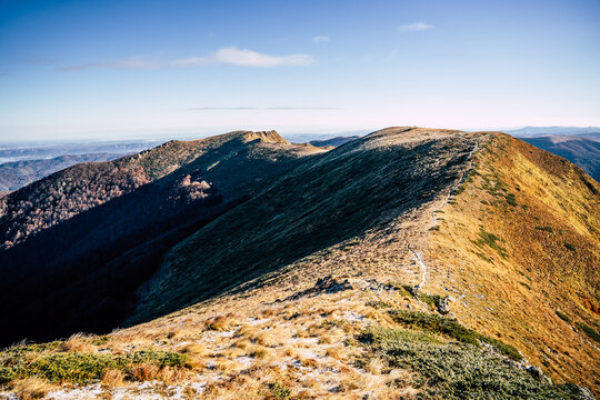 View of the mountain ridge near Golyam Kademliya Shelter with golden autumn grasses and rocky terrain under a clear blue sky in Stara Zagora, Bulgaria.