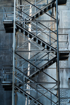 View of an industrial metal staircase attached to a riveted steel wall with geometric structural details in Ostrava, Moravian-Silesian Reg, Czechia.