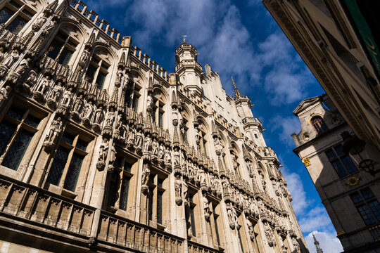 View of the ornate Gothic facade of the Maison du Roi with intricate stone sculptures and statues under a blue sky in Brussels, Brussels, Belgium.